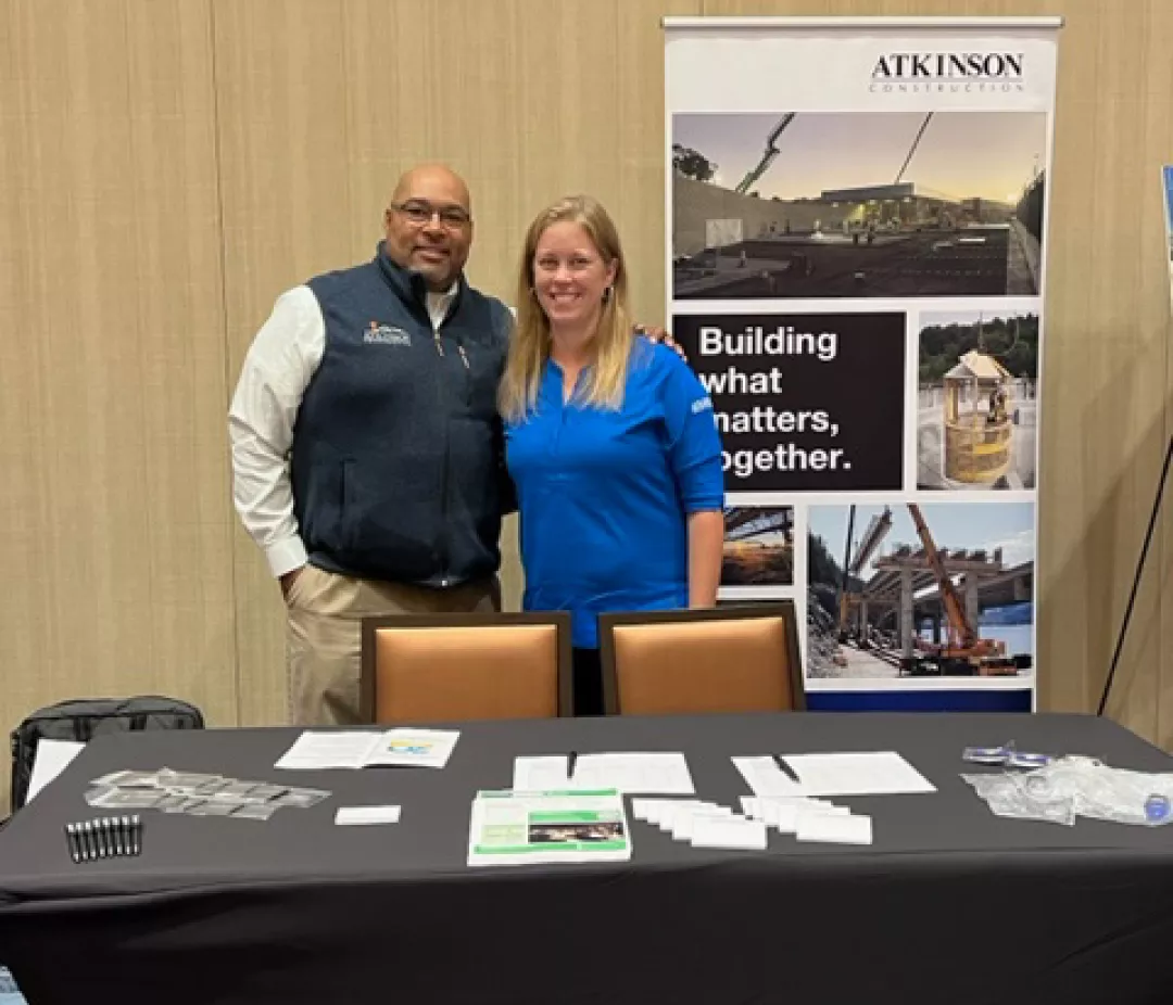 Atkinson booth with branded banner and tablecloth, with Karlton and Natalie