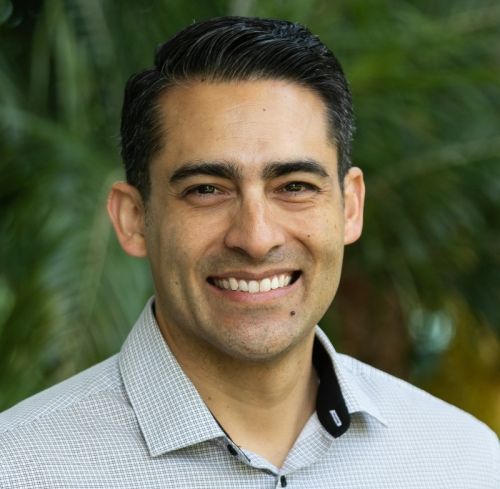 Chris Acosta smiling headshot photo with green background 